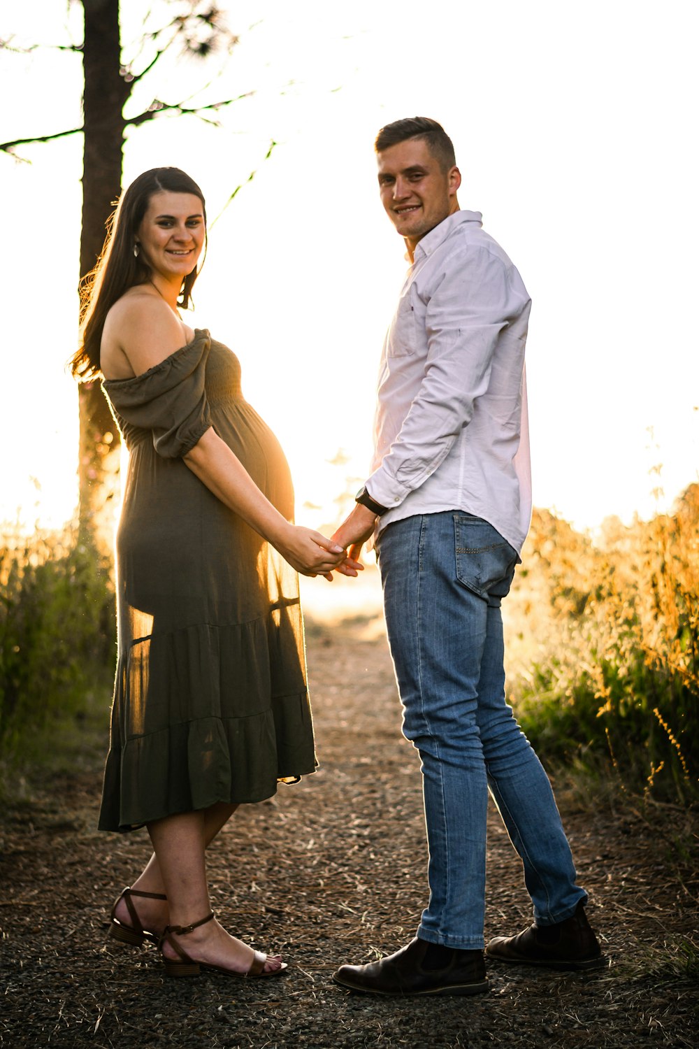 man and woman holding hands while walking on pathway