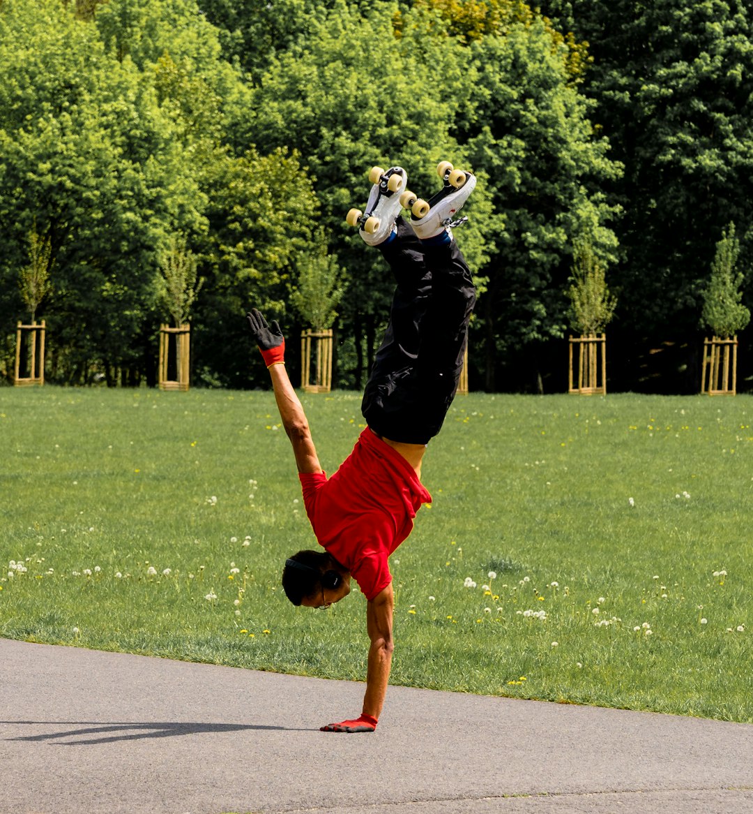 man in white long sleeve shirt and red shorts jumping on green grass field during daytime