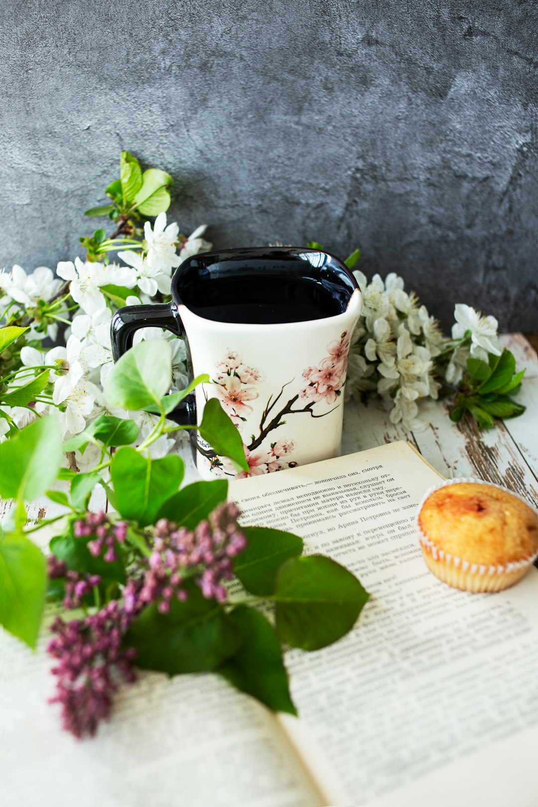 white ceramic mug with coffee beside pink flowers