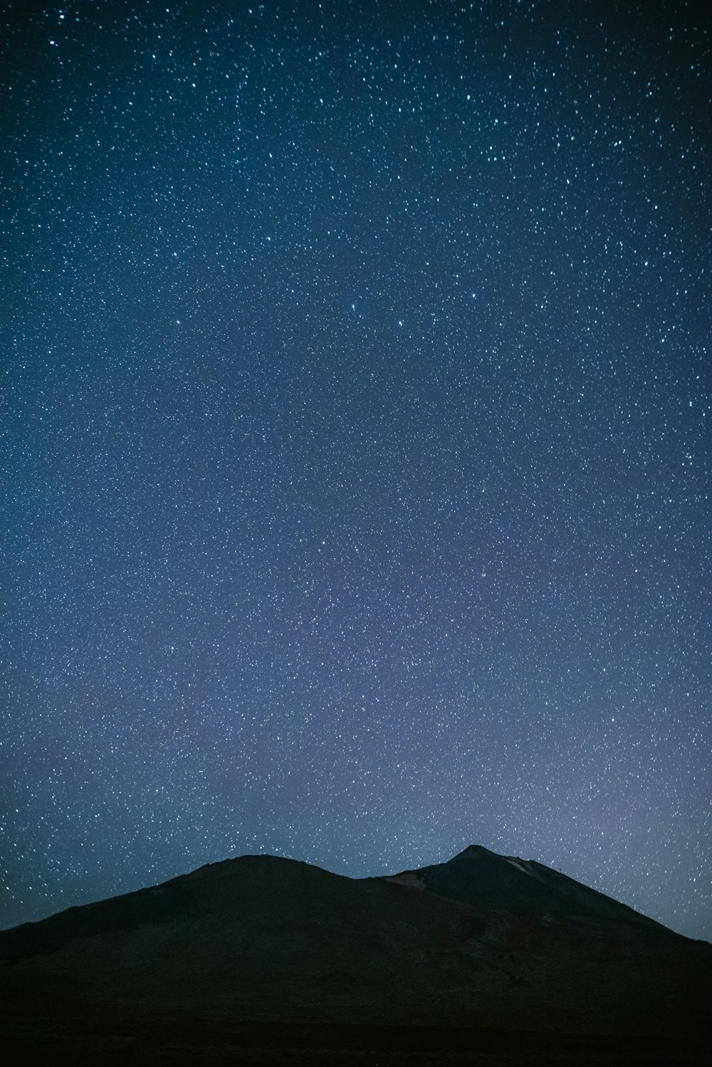 silhouette of mountain under blue sky during night time