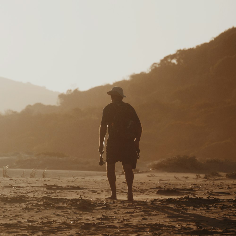 silhouette of man standing on seashore during daytime