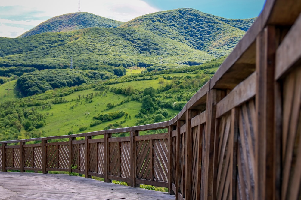 brown wooden bridge over green mountains during daytime