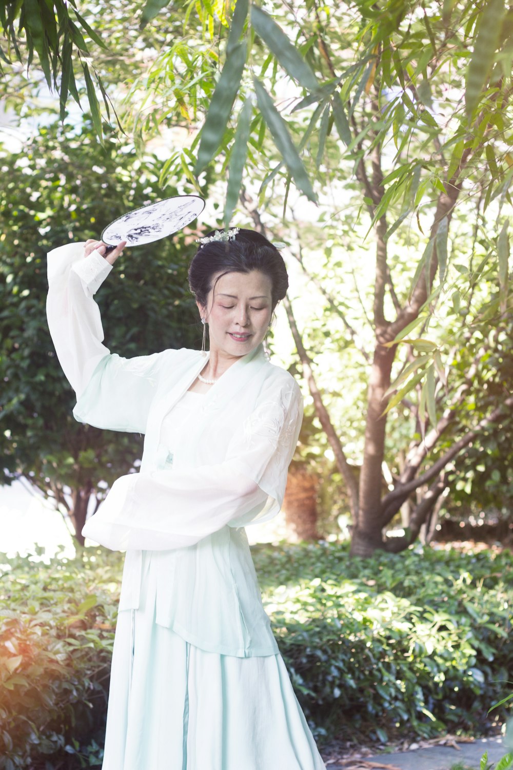 woman in white long sleeve dress holding white hand fan