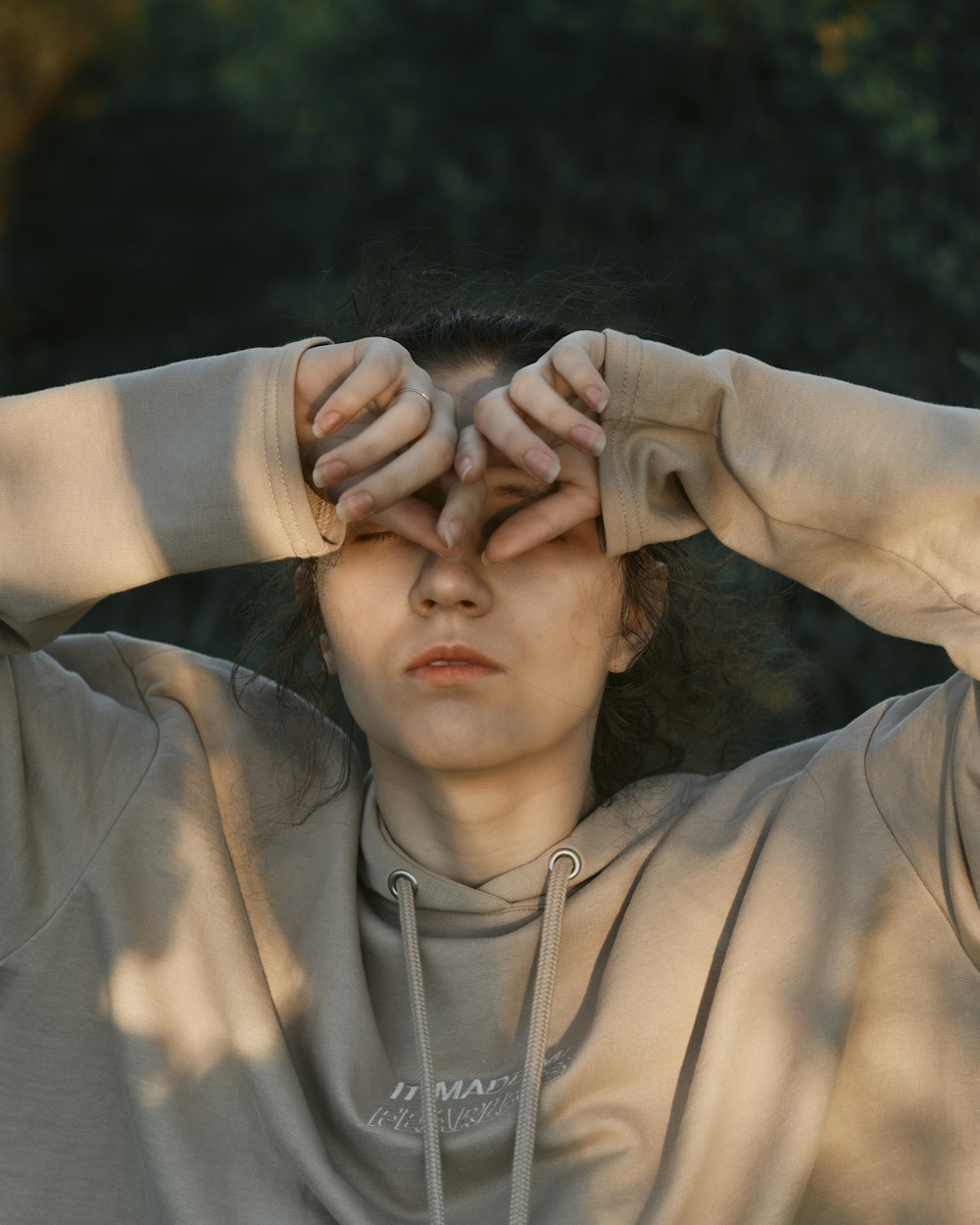 man in gray zip up jacket covering face with hands