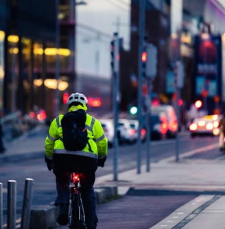 man in green and black jacket riding bicycle on road during daytime