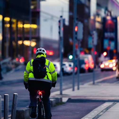 man in green and black jacket riding bicycle on road during daytime