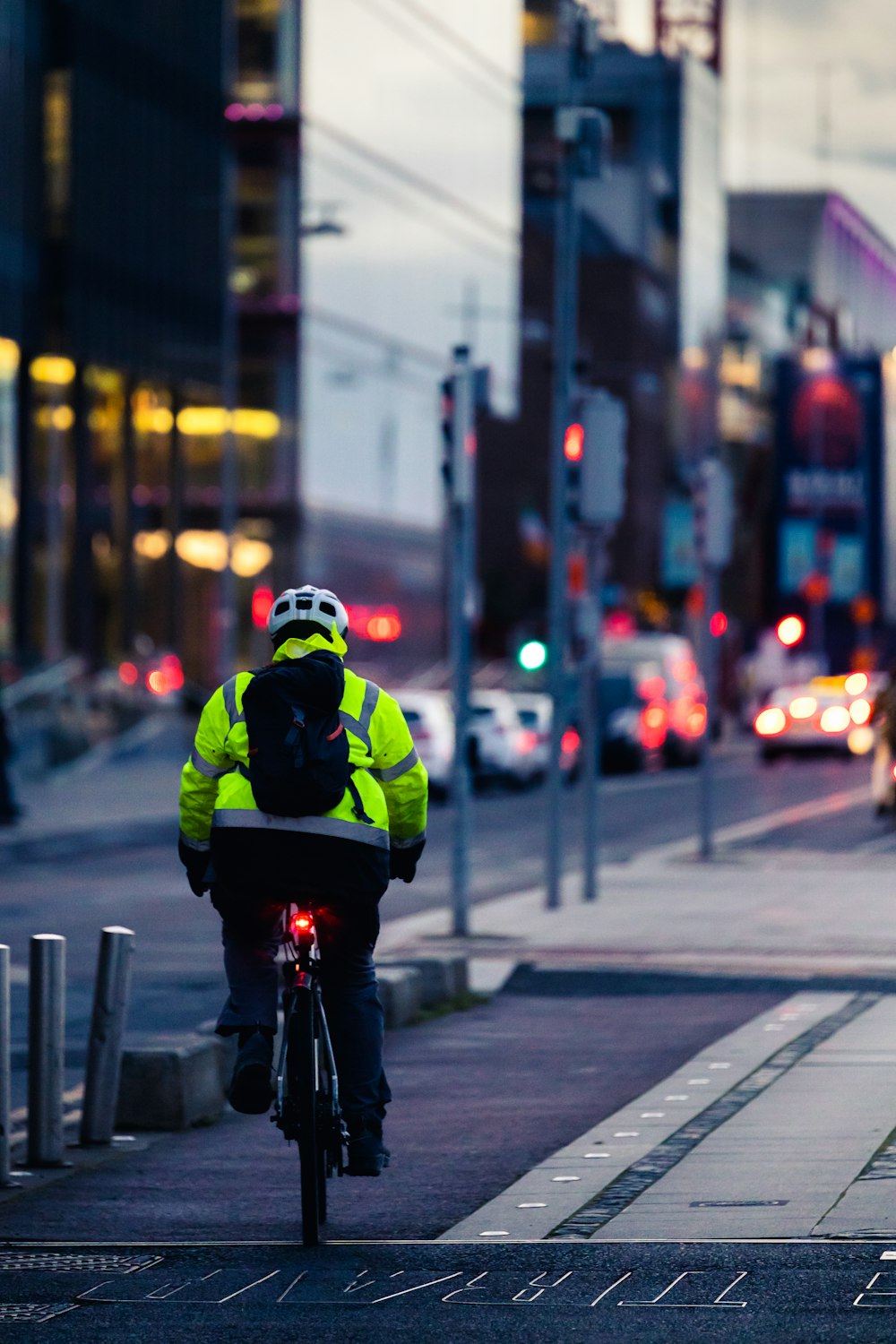 Mann in grüner und schwarzer Jacke fährt tagsüber Fahrrad auf der Straße