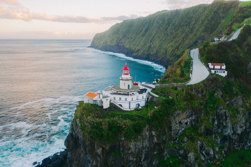 Edificio de hormigón blanco en la montaña verde junto al mar durante el día