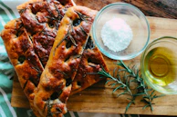 Artisanal focaccia bread topped with fresh rosemary and sea salt, photographed with soft natural light.