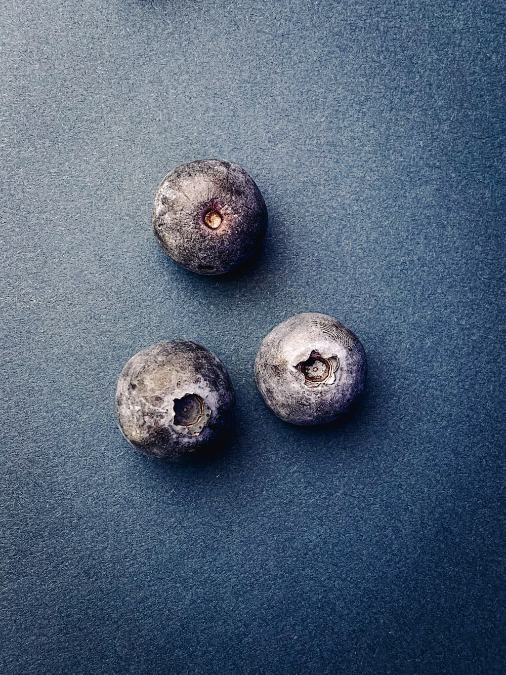 six round gray fruits on gray surface