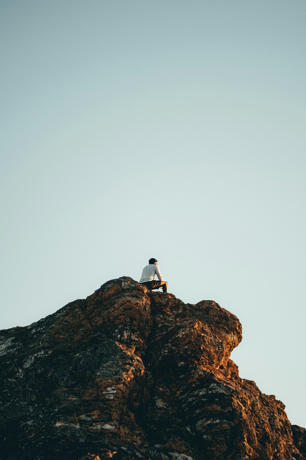 man in white shirt standing on brown rock formation during daytime