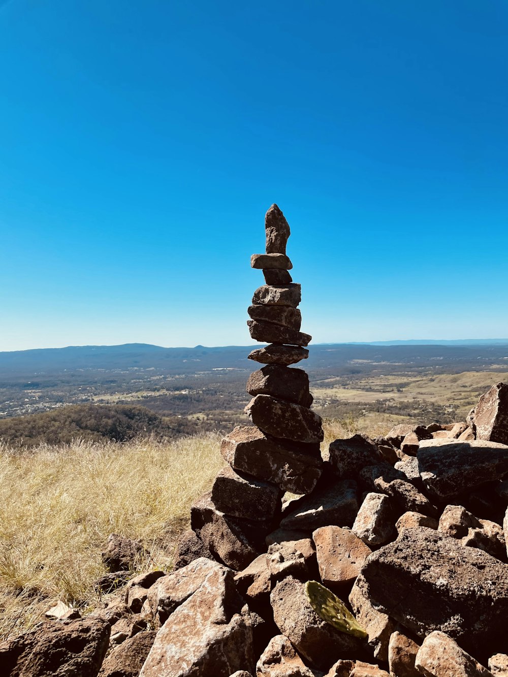 stack of stones on brown grass field under blue sky during daytime