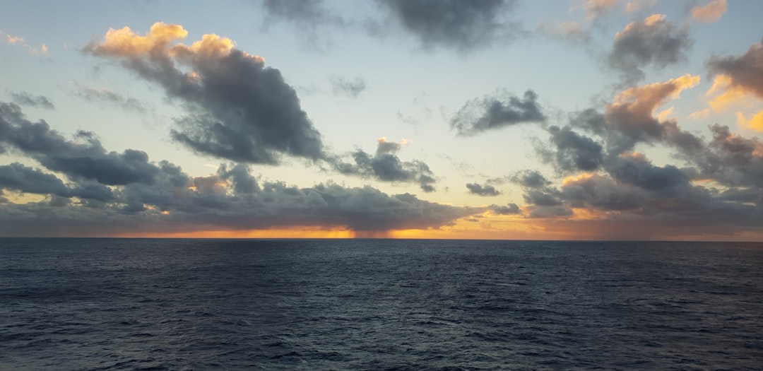 body of water under cloudy sky during sunset