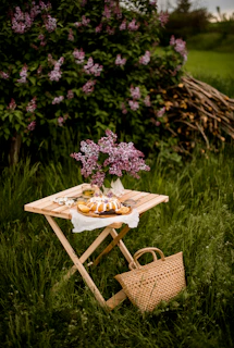 A rustic wooden table showcasing a cake decorated with fresh lilacs and soft purple icing.