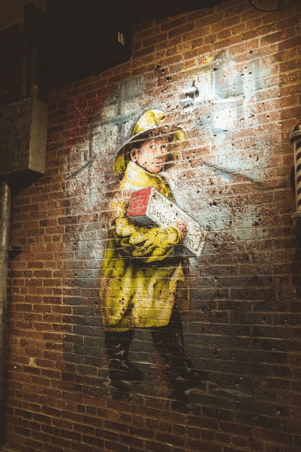 man in yellow jacket and black helmet leaning on brown brick wall