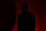 silhouette of man standing in front of red wall