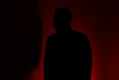 silhouette of man standing in front of red wall