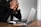 A person is sitting at a table with a laptop in front of them, holding their head in frustration. Glasses and a smartphone are also on the table, suggesting a work or study environment.