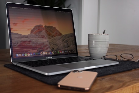 A sleek laptop and tablet arranged on a desk with a coffee cup.