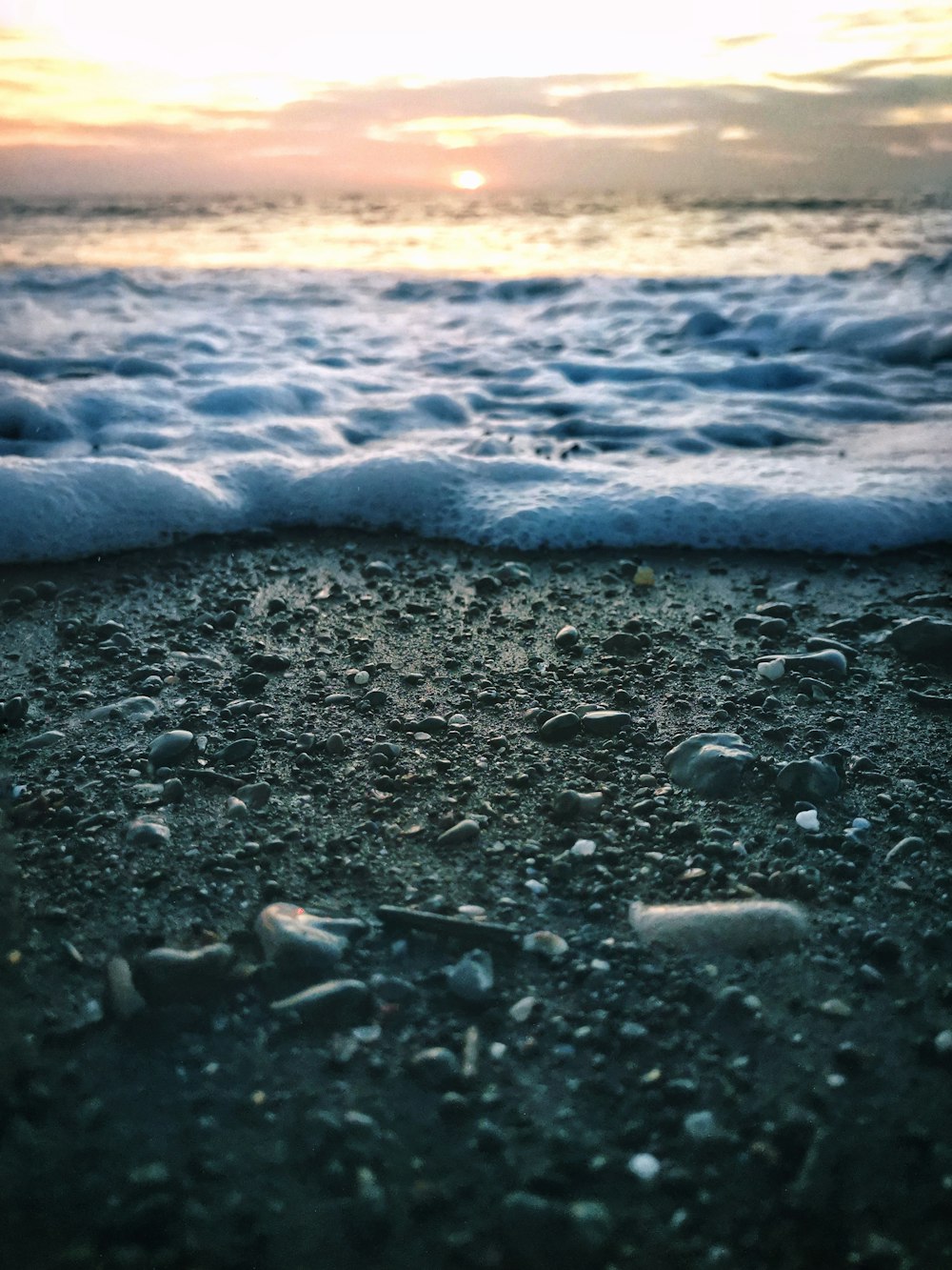 water waves on gray sand during sunset