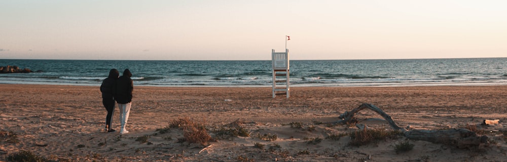 white wooden lifeguard tower on brown sand near sea during daytime