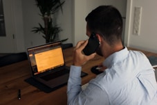 man in blue dress shirt holding black smartphone