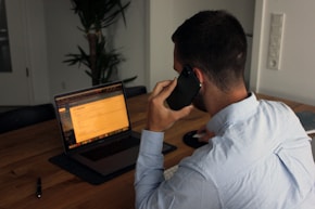 man in blue dress shirt holding black smartphone