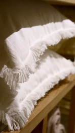 A selection of plush pillows arranged neatly on a wooden shelf.
