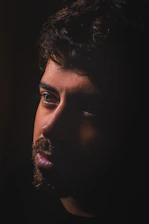 A close-up of a tearful face illuminated by soft light against a dark background.
