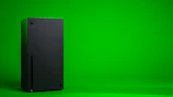 A sleek Xbox Series X console standing on a wooden table with a glowing green light.