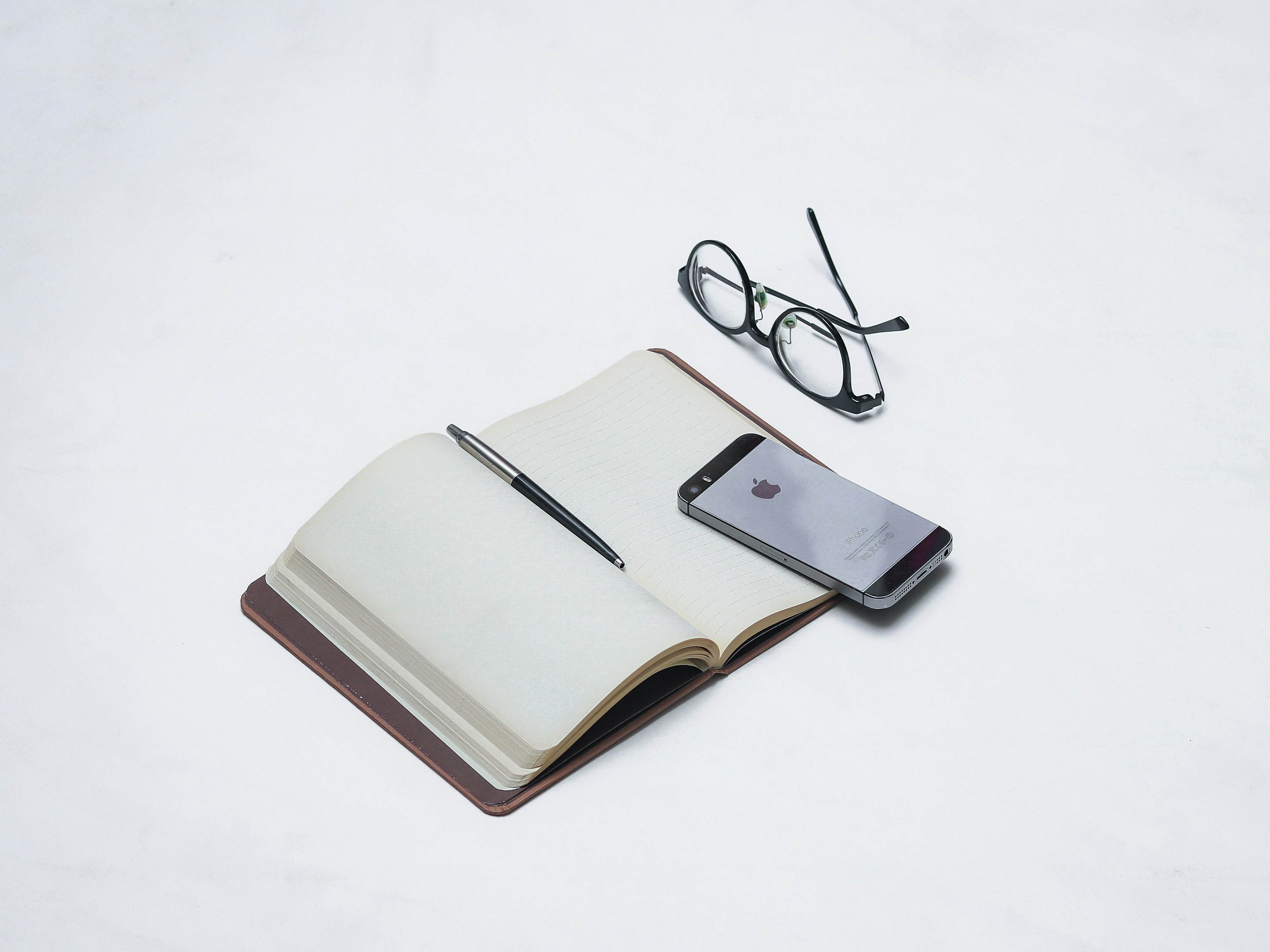 schwarz gerahmte Brille auf weißem und braunem Buch