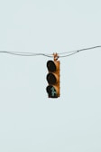 A traffic light suspended in the air by wires with a green light illuminated and a teal-colored background.