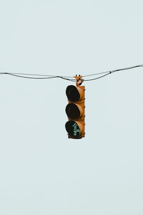 A traffic light suspended in the air by wires with a green light illuminated and a teal-colored background.