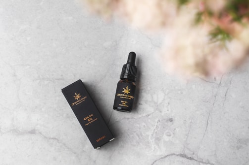 Close-up of golden CBD oil drops glistening on a sleek black surface.