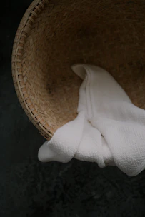 A neatly woven linen basket holding rolled towels in a cozy bathroom corner.
