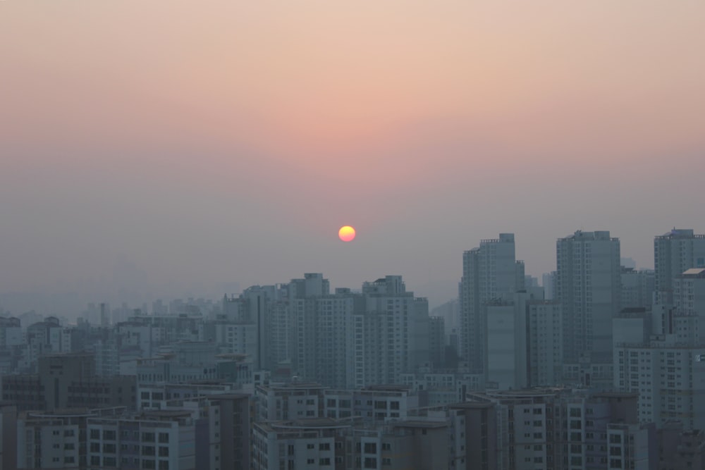 city buildings under orange sky during daytime