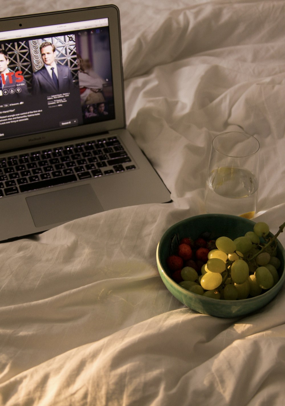 green round fruit on green plastic bowl beside macbook pro