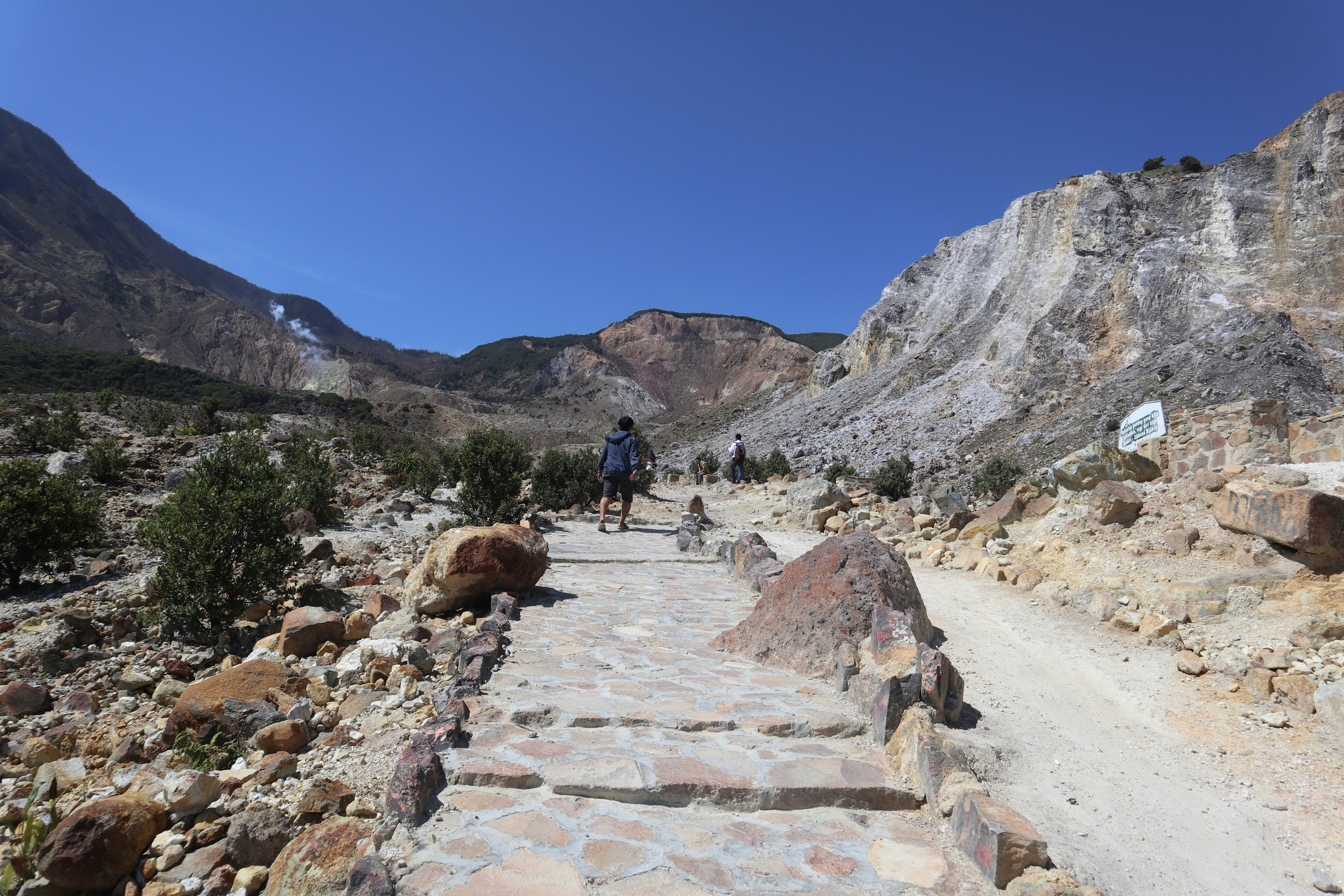 people walking on rocky road near rocky mountain during daytime