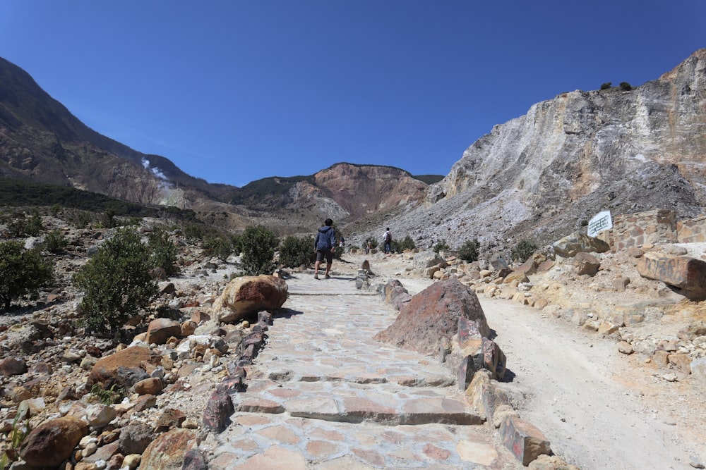 people walking on rocky road near rocky mountain during daytime