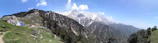 A panoramic view of an Asian mountain range with a van camped at the base.