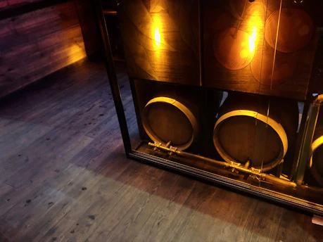 A rustic brewery interior with wooden barrels and warm lighting, evoking a cozy, industrial atmosphere.
