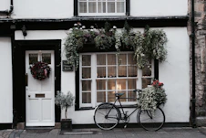 black city bike parked beside white and brown house during daytime