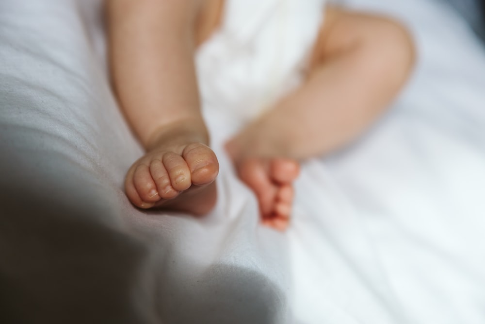 baby lying on white textile