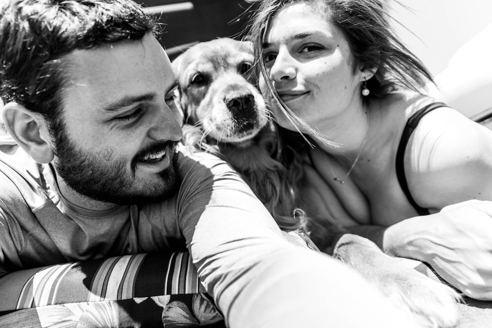 man and woman with dog grayscale photo