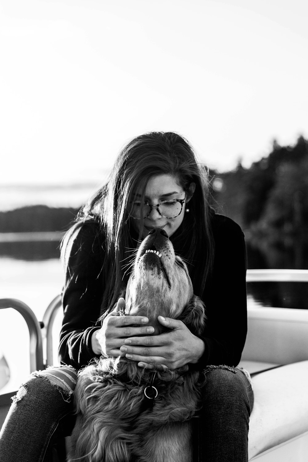 woman in black long sleeve shirt holding dog in grayscale photography