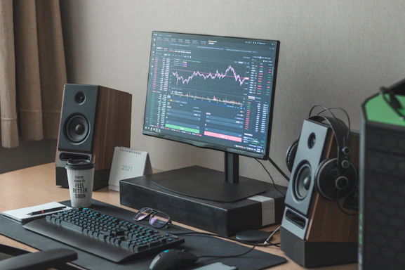 A calm, organized workspace with a laptop displaying financial charts and a neatly arranged notebook beside it.