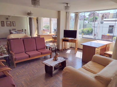 Living room of a 4BHK flat with elegant decor and ample sunlight.