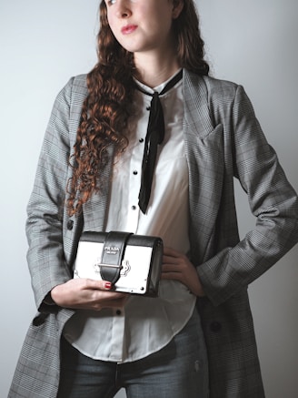 woman in gray blazer holding black and white camera