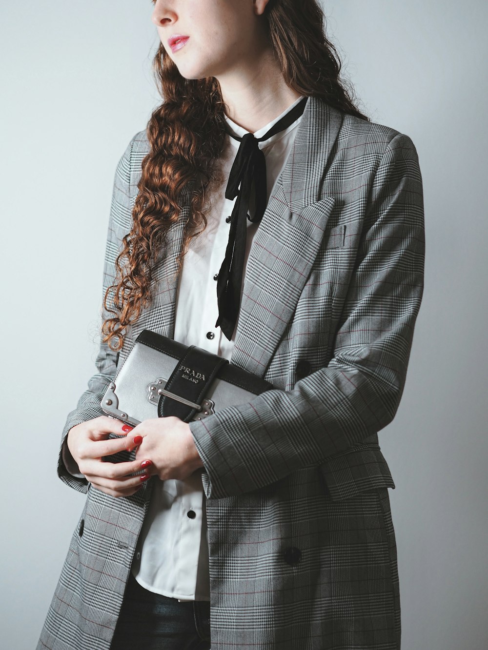 woman in black and white plaid blazer holding silver iphone 6