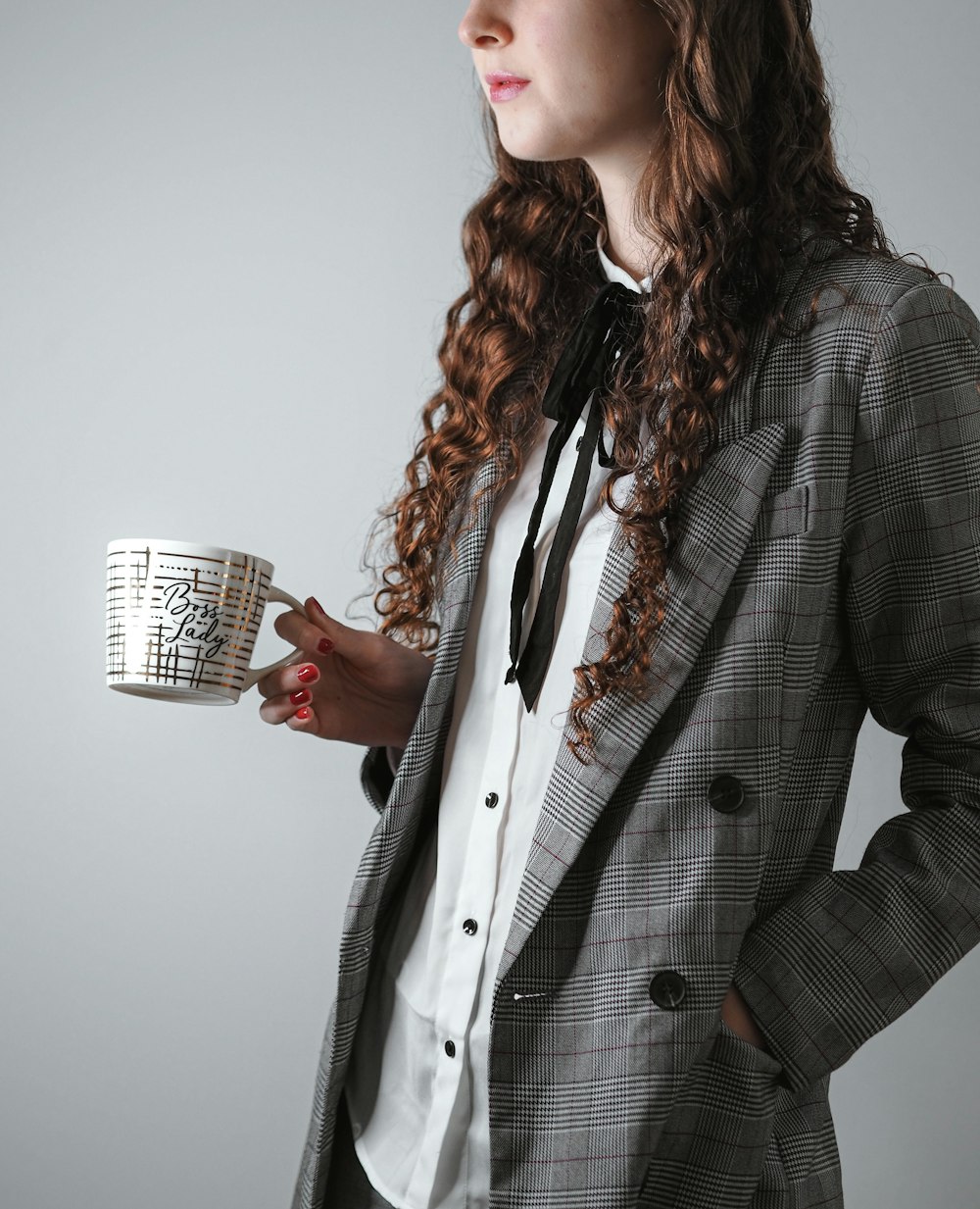 woman in black and white polka dot blazer holding silver cup